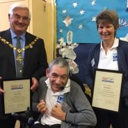 Man in wheelchair with the Mayor and a female holding certificates.