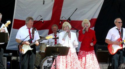 Band singing and playing on a stage.