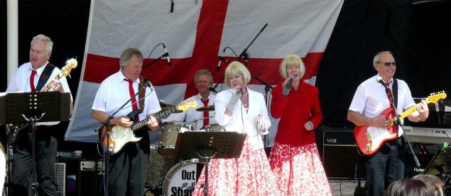 Band singing and playing on a stage.