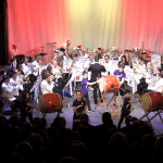 Orchestra and drummers on stage.