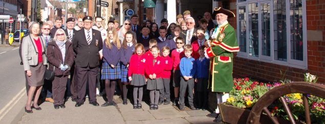 Group of adults and schoolchildren in front of red brick building