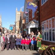 Group of adults and schoolchildren in front of red brick building