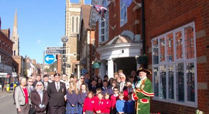 Group of adults and schoolchildren in front of red brick building