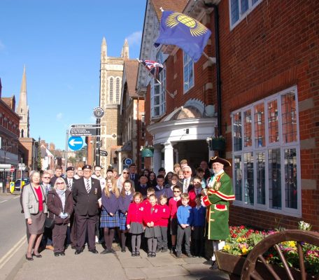 Group of adults and schoolchildren in front of red brick building