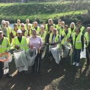 Group of people in high viz jackets holding sacks and litter picks