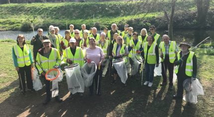 Group of people in high viz jackets holding sacks and litter picks