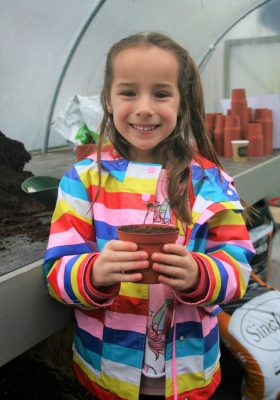 Smiling girl holding a flower pot.