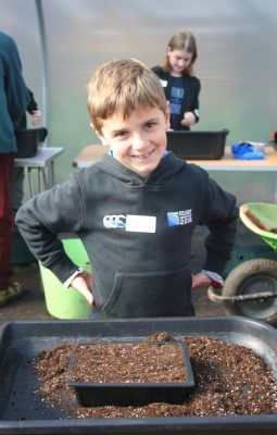 Smiling boy with a seed tray.