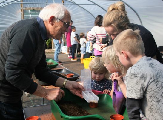 Man shows children a container of seeds.