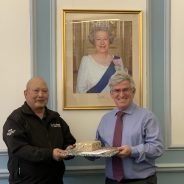 Man presents gift wrapped items to man on his right.