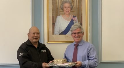 Man presents gift wrapped items to man on his right.