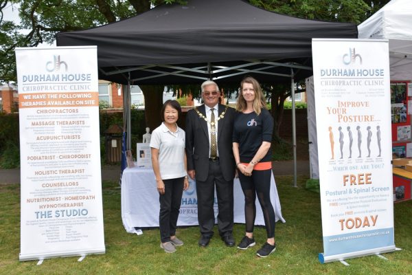 Male Mayor with two females standing in front of a stall at a Festival