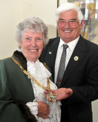 Female Mayor standing next to a man in suit holding the Mayoral chain.