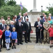 Group of adults and children standing in front of war memorial