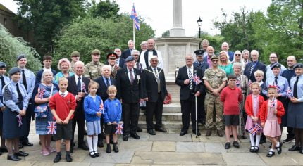 Group of adults and children standing in front of war memorial