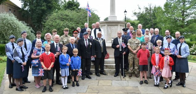 Group of adults and children standing in front of war memorial