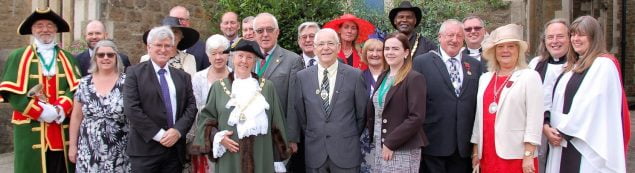 Mayor with group of people in smart clothes standing outside church.