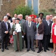 Mayor with group of people in smart clothes standing outside church.