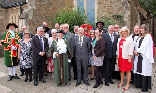 Mayor with group of people in smart clothes standing outside church.