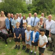 Group of adults and children in a green space.