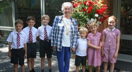 School children with the Mayor of Farnham in front of a hanging basket.