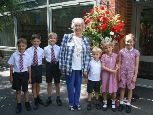 School children with the Mayor of Farnham in front of a hanging basket.