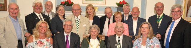 Group of people standing and sitting close together.