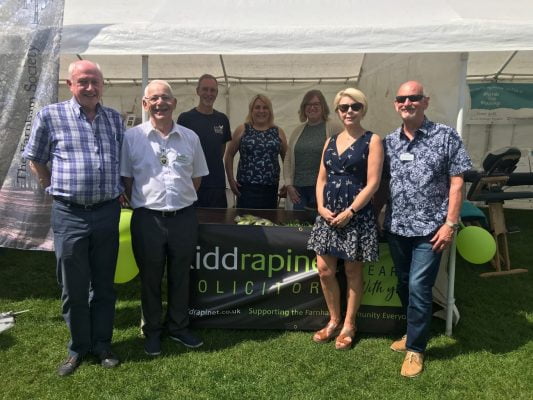 Group of people standing in front of a small marquee.