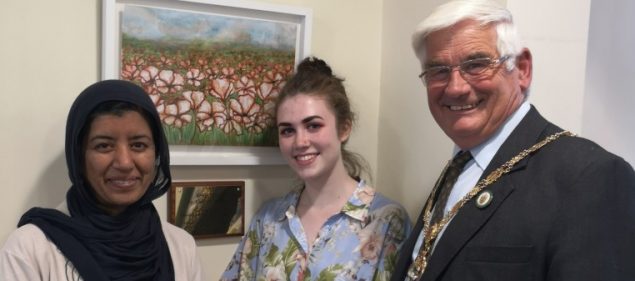 Three people standing in front of a poppy picture