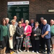 Group of people standing in front of a sign.