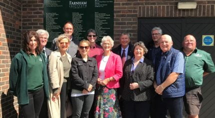 Group of people standing in front of a sign.