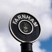 Black circular sign post with Farnham painted in white letters around top of circle