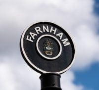 Black circular sign post with Farnham painted in white letters around top of circle