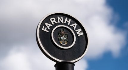 Black circular sign post with Farnham painted in white letters around top of circle