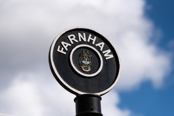 Black circular sign post with Farnham painted in white letters around top of circle