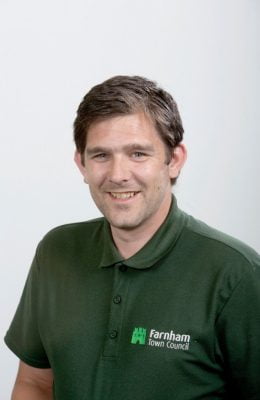 Smiling man wearing green Farnham Town Council polo shirt