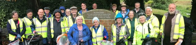 Group of litter pickers in high viz jackets and holding bags and litter picks