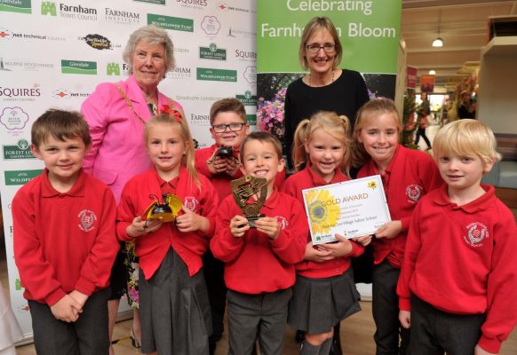 Schoolchildren holding trophies and a certificate.