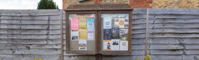 Wooden noticeboard displaying posters
