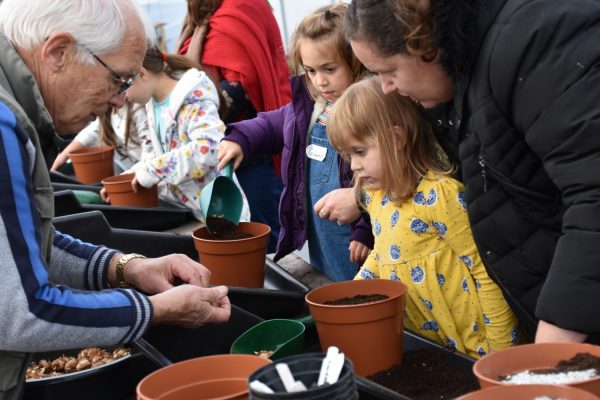 Adult showing children how to plant seeds.