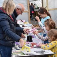 Two adults showing children a craft activity.