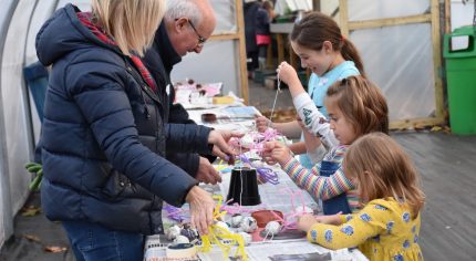 Two adults showing children a craft activity.