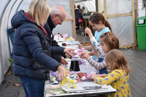 Two adults showing children a craft activity.