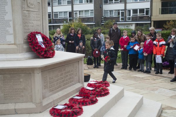 Girl places cross and wreath on war memorial