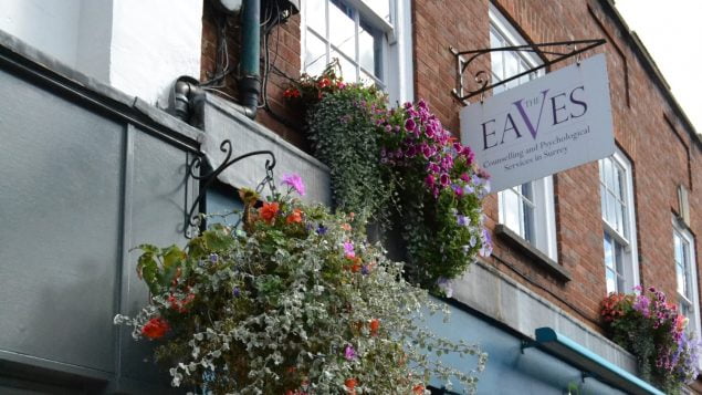 Sign and hanging baskets on side of building
