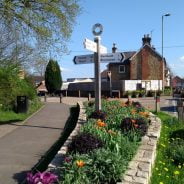 Street scene with wooden directional sign and flowers