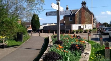 Street scene with wooden directional sign and flowers