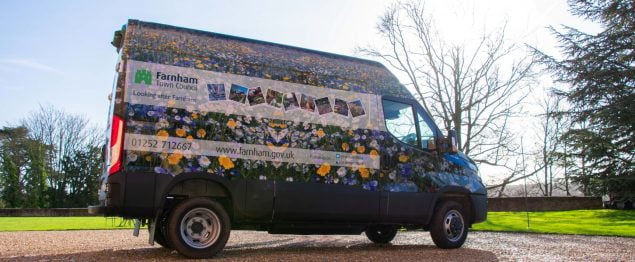 Van covered in images of flowers. Parked on a gravel drive