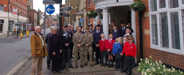 Group of people including soldiers, veterans and school children in front of town hall building