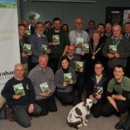 Group of people holding a booklet. Dog in foreground